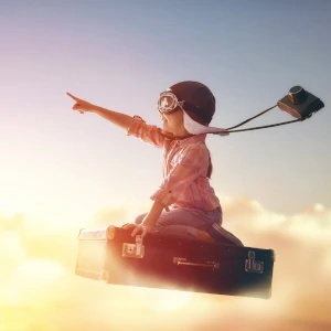 Oser le jeu et la créativité - Enfant volant dans le ciel sur une valise avec des lunettes et casque d'aviation rétro